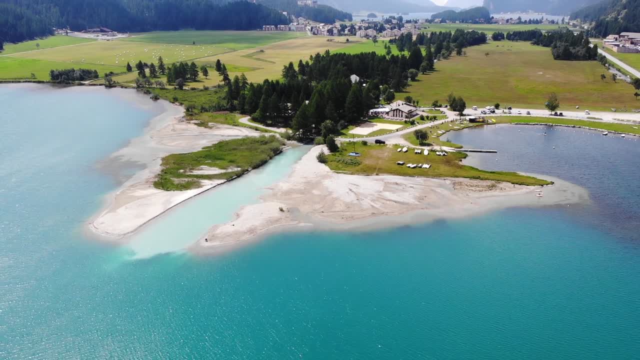 Aerial drone shot captures idyllic Swiss coastline, where serene sea meets vibrant green landscape during daytime, offering breathtaking view of Switzerland's natural beauty