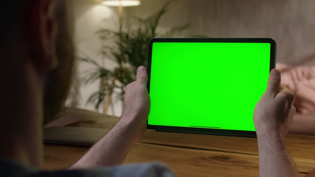 Handheld Camera: Over The Shoulder View Man Using Hand Gestures on Green Mock-up Screen Digital Tablet Computer in Landscape Mode. Tapping on Center Screen