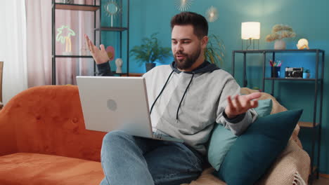 Man-sitting-on-home-couch,-looking-at-camera,-making-video-conference-call-with-friends-or-family