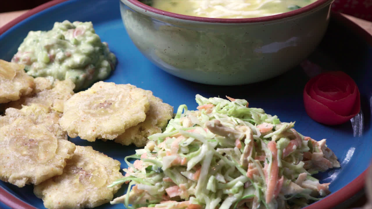 Traditional Ecuadorian lunch with aji sauce featuring patacones, coleslaw, and avocado dip