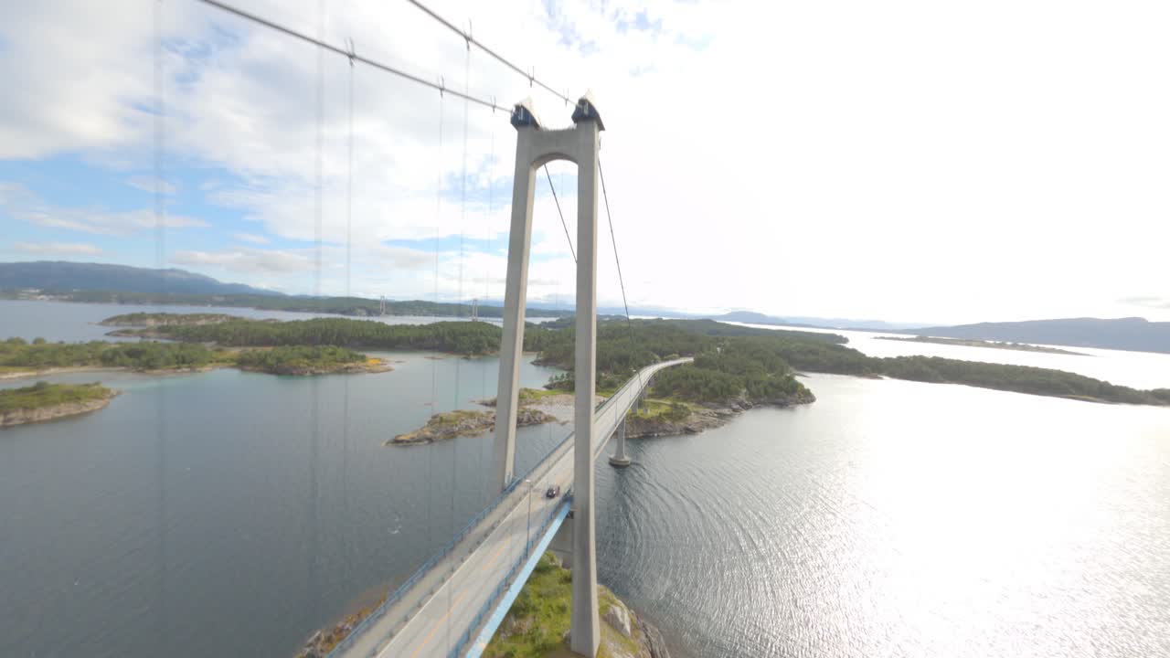 Aerial fpv flight of car driving over suspension bridge in Norway during summer