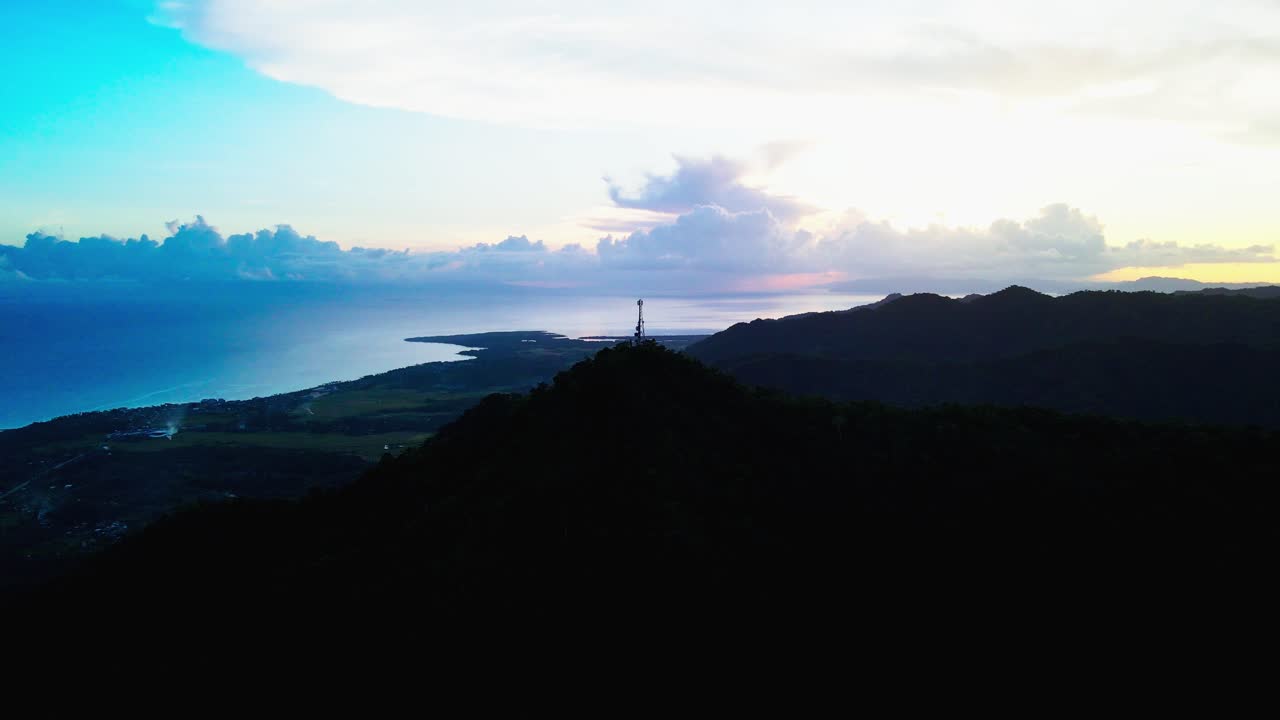Picturesque silhouette outline of lush Mount Cagmasuso and satellite tower with stunning, vibrant cloud background at Catanduanes, Bicol, Philippines - aerial drone shot