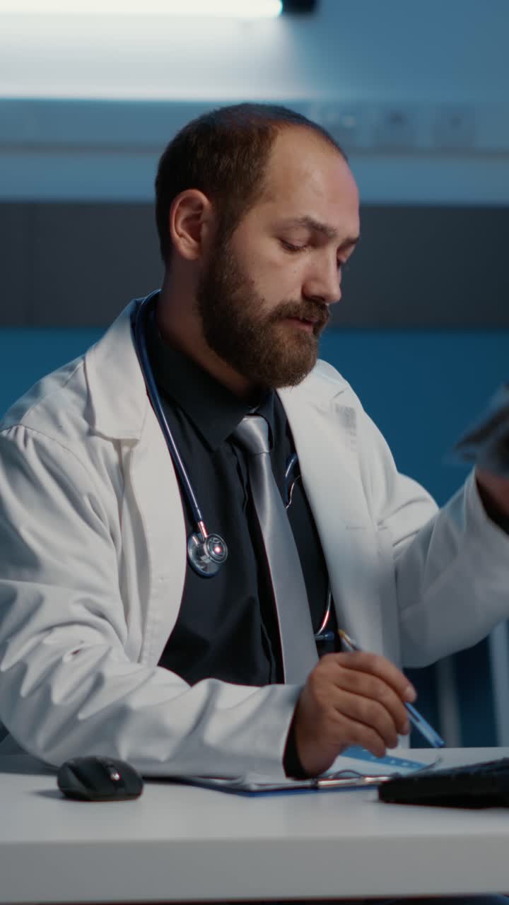 Video verticale: medico che analizza radiografie e digita competenze mediche al computer