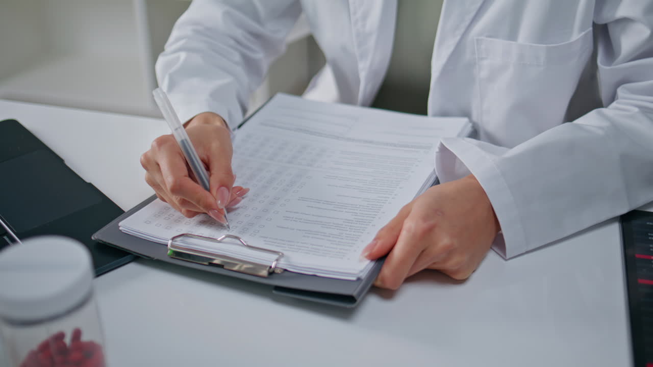 Specialist filling medical paperwork at clinic closeup. Unknown doctor writing