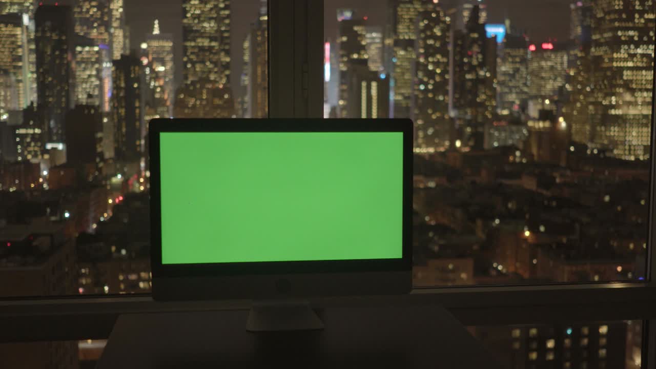 computer con schermo verde in un moderno edificio per uffici con lo sfondo del paesaggio cittadino.