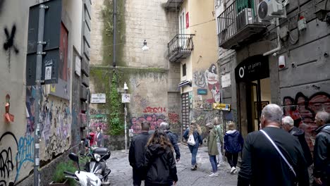 group of tourists walking along naples street past graffiti walls on walking tour