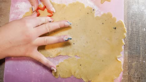 Close-up-top-view-of-a-female-hand-making-a-gingerbread-cookie-in-the-form-of-a-star