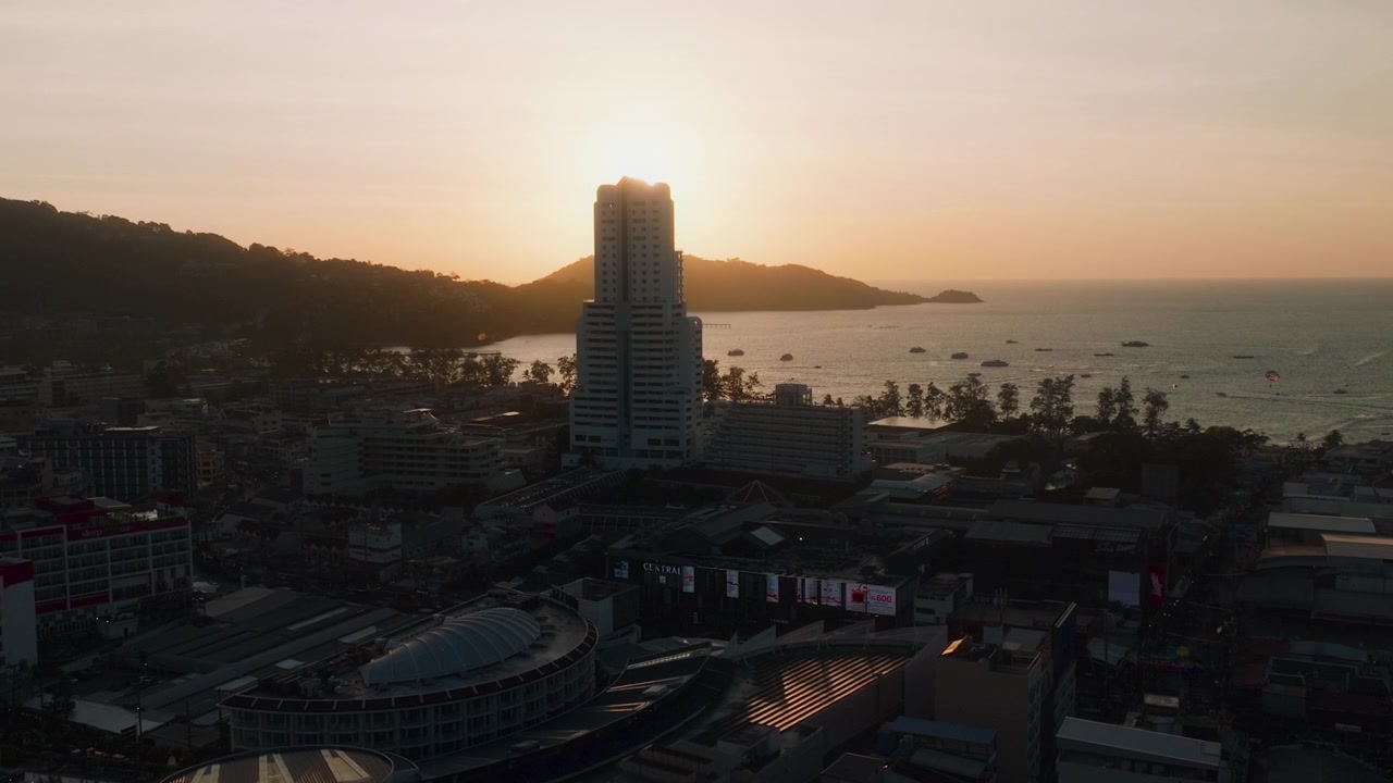 Drone che scende verso la Patong Tower con il tramonto sulla baia di Phuket