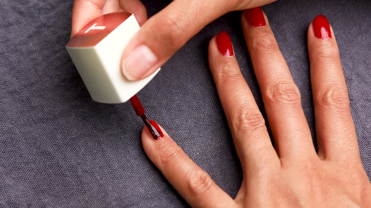mujer pintándose las uñas con esmalte de uñas rojo
