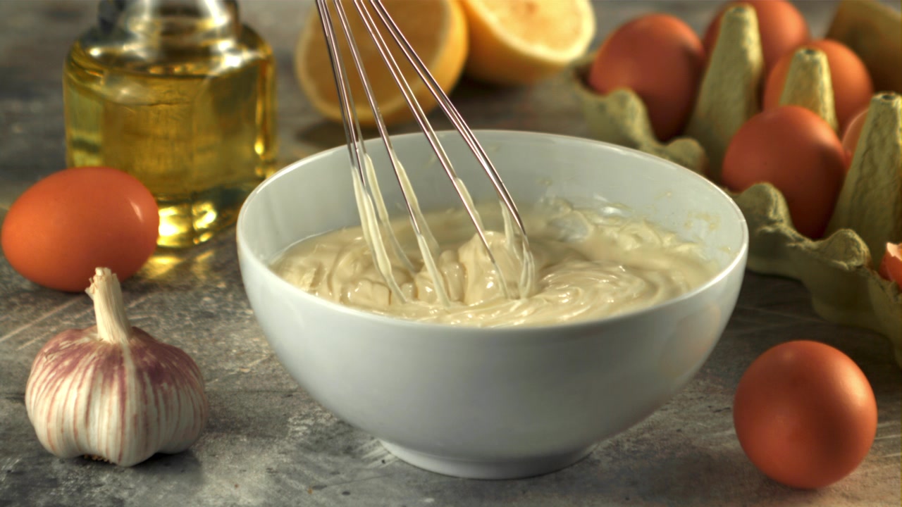 Whisking Homemade Mayonnaise in a White Bowl with Fresh Ingredients