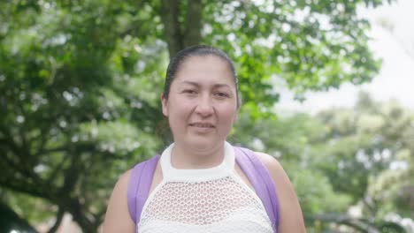 close-view-of-smiling-Colombian-woman-with-earrings-framed-by-lush-trees