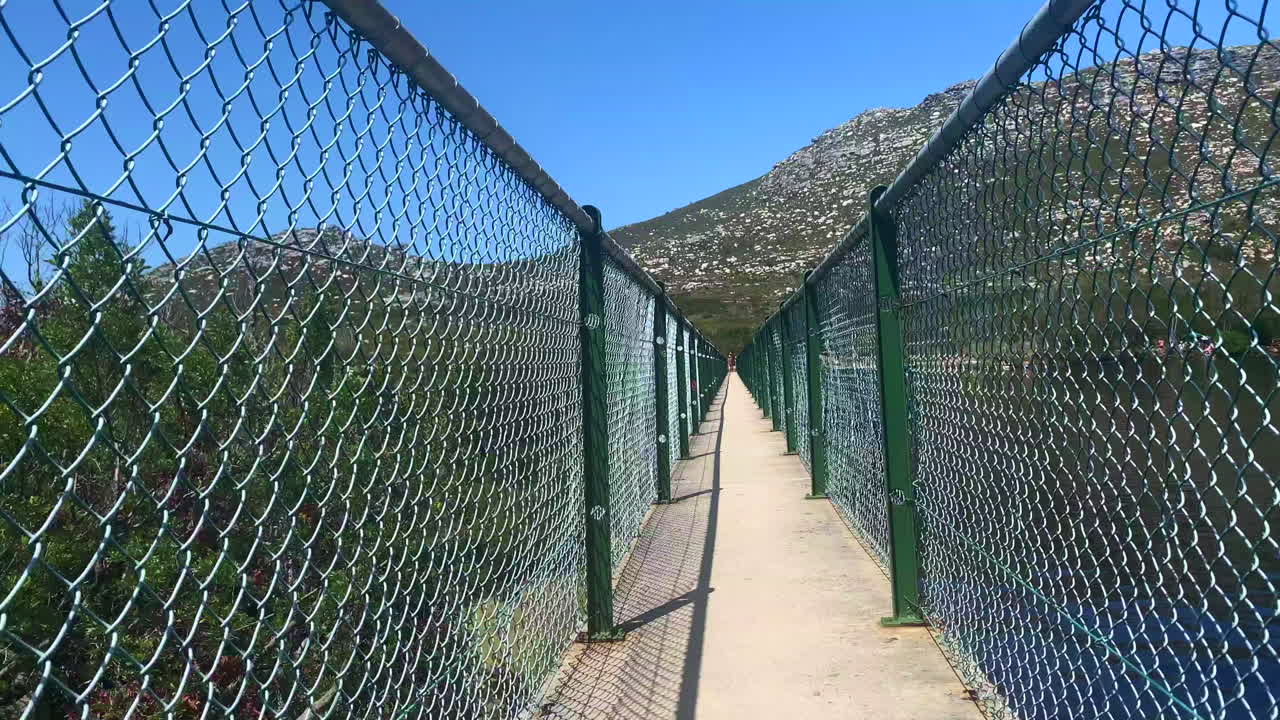 walking along a fenced dam wall in the Silvermine section of Table Mountain National Park in Cape Town South Africa