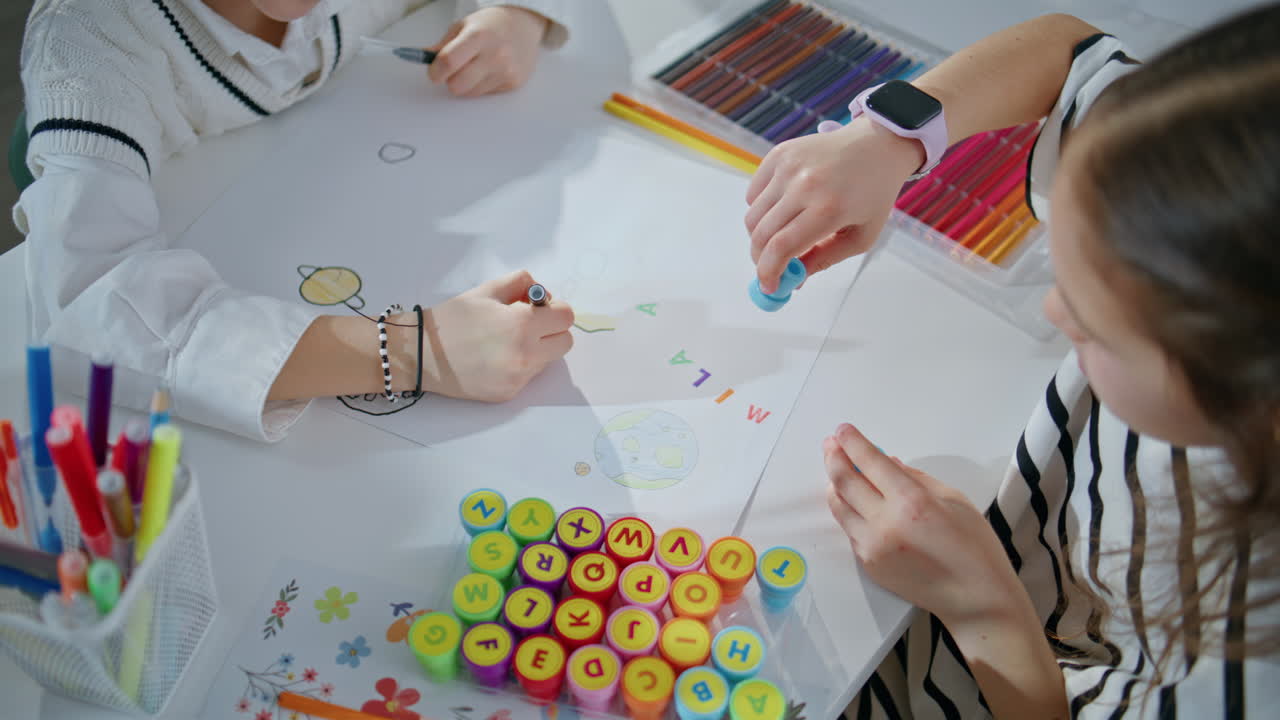 Involved kid playing stamps enjoying art lesson in school class room closeup