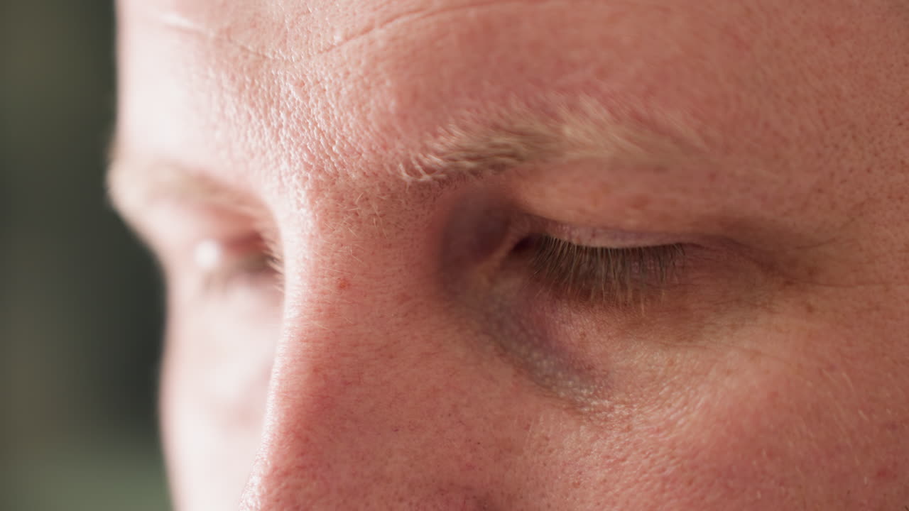 기술자의 얼굴의 클로즈업 뷰, 강렬한 집중과 초점을 강조하고, 흐릿한 녹색 배경