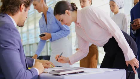 Business-people-checking-in-at-conference-registration-table-4k