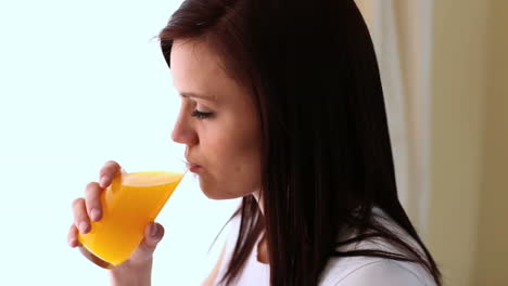 una mujer joven bebiendo jugo de naranja.