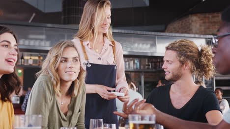 customer making contactless payment on mobile phone to waitress for meal in restaurant