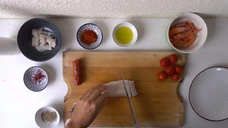 male hands preparing squid seafood for spanish paella on wooden cutitng board