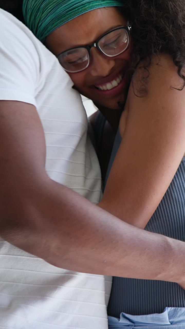 Couple exchanging test stick, reading result, embracing with health icon appearing over stick