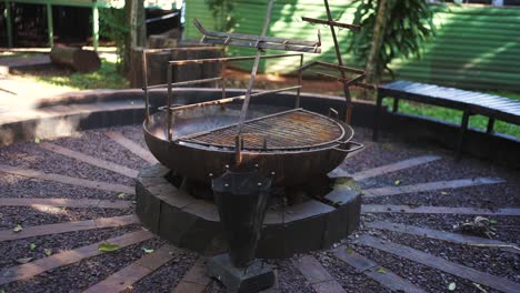 large outdoor bbq grill stands in a rustic garden with a stone pathway, surrounded by greenery and benches, ready for a cookout