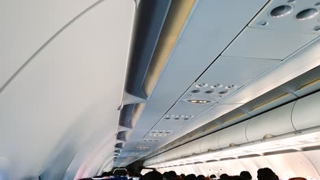 cabin of an airplane during take off showing seated passengers, with seatbelt sign on