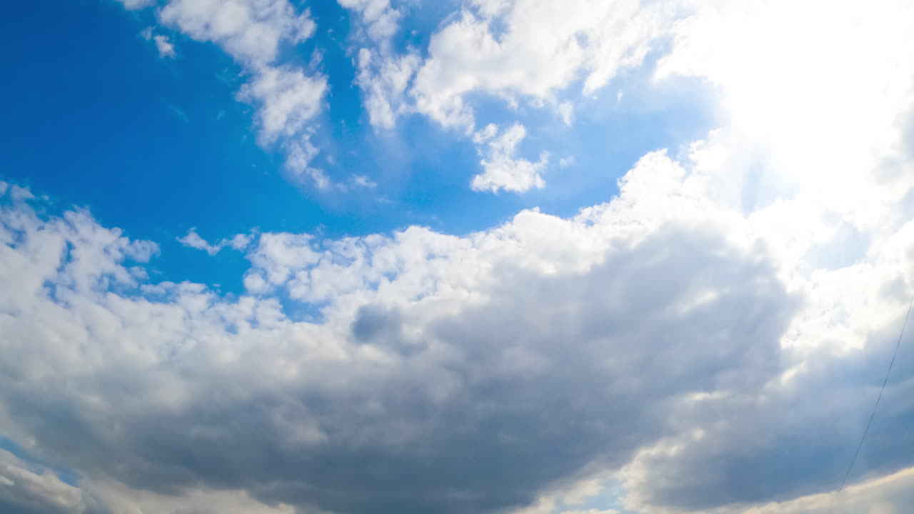 Huge white soft cloud lit by the bright sun changes its shape in the wind. Cloudy sky in summer. View from below. Timelapse.