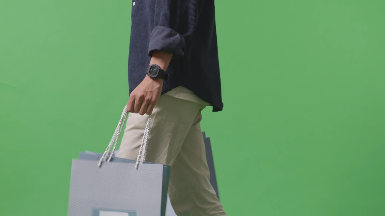 초록색 스크린 앞에서 는 쇼핑 가방을 가진 쇼핑맨의 측면 시각
