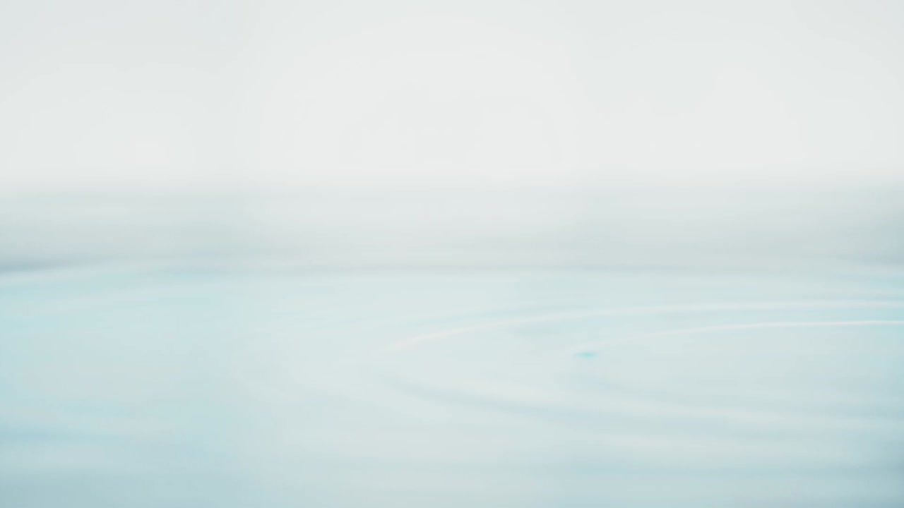 슬로우 모션의 깨끗한 물 표면은 물이 튀는 상점으로 화면을 채우고 기포로 액체 표면을 흔들고 있습니다.