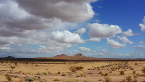 volando lento sobre el impresionante paisaje marrón del desierto de mojave con montañas en la distancia - tiro aéreo bajo
