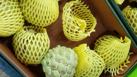 woman of african ethnicity shopping for a custard apple on a market stall