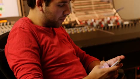 ingenieros de audio masculinos mensajería de texto en teléfono móvil