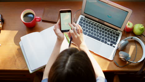 mujer trabajando en un escritorio con portátil, teléfono inteligente y café