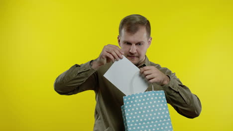 man showing up to 70 percent off inscription from shopping bag, rejoicing discounts, low prices