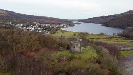 una vista aérea del castillo de dolbadarn en un día nublado, volando de izquierda a derecha alrededor del castillo con un zoom lento y la ciudad de llanberis al fondo, gwynedd, gales, reino unido