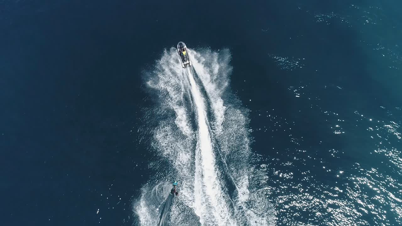 Jet Ski and surf rider on jet skiing on tropical blue and green sea waterscape. Top down aerial footage of sport activity with ocean waves ripple. beautiful high adrenaline and extreme sports scene.