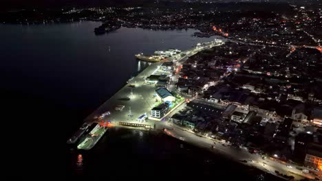 Hermosa-Antena-Sobre-El-Puerto-De-La-Ciudad-De-Suriago-Por-La-Noche-Con-Aguas-Azul-Oscuro