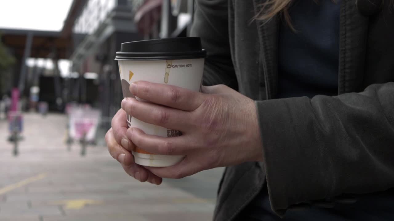 Hands holding coffee take out cup in city medium shot