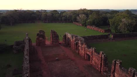 Panning-aerial-footage-shot-of-the-mission-ruins-of-San-Ignacio,-Misiones,-Argentina-surrounded-by-a-luscious-green-forest