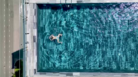 woman swims on the rooftop pool of a hotel in da nang city, vietnam. - overhead shot