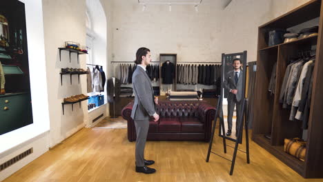 young man trying on suit and tie in front of mirror in classy boutique