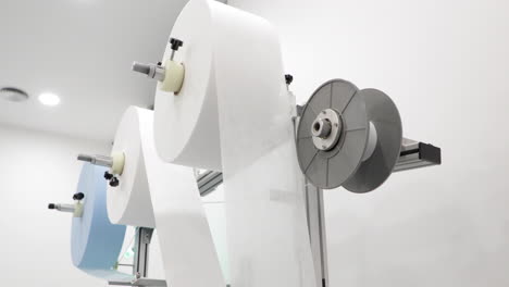 Rotating-Rolls-Of-Non-woven-Raw-Fabric-Material-On-Machine