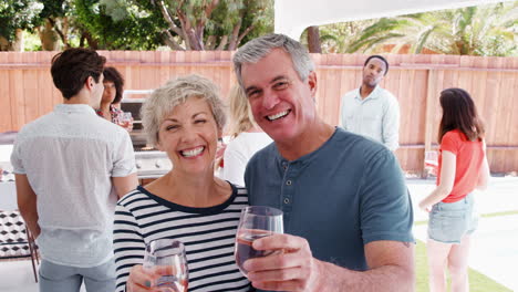 senior couple at a backyard party raising glasses to camera