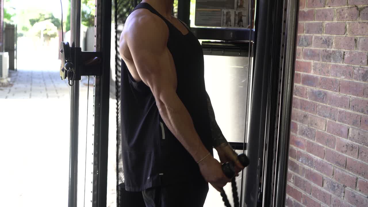 tatuaje hombre músculos en casa gimnasio cable bicep curl entrenamiento