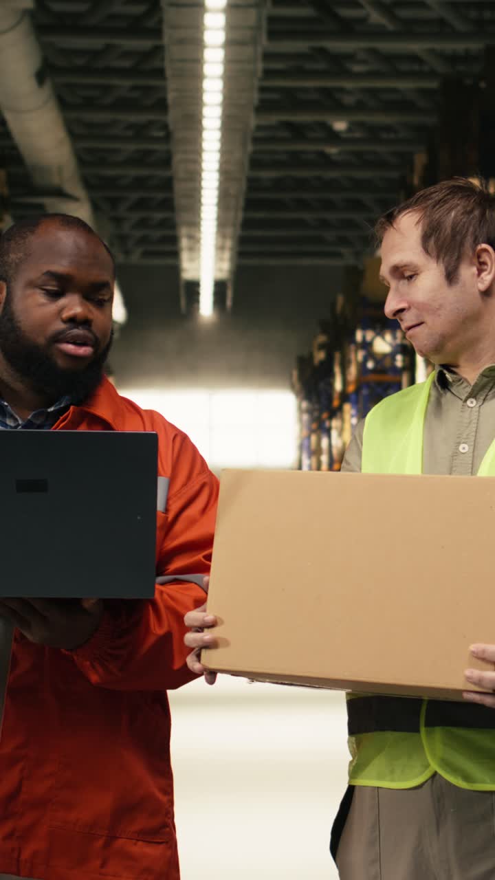 Vidéo verticale : collaborateurs rangeant des boîtes en carton sur étagères et faisant l'inventaire sur ordinateur portable.