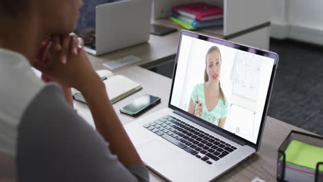 sección media de una mujer afroamericana haciendo una videollamada con una colega en una computadora portátil en la oficina