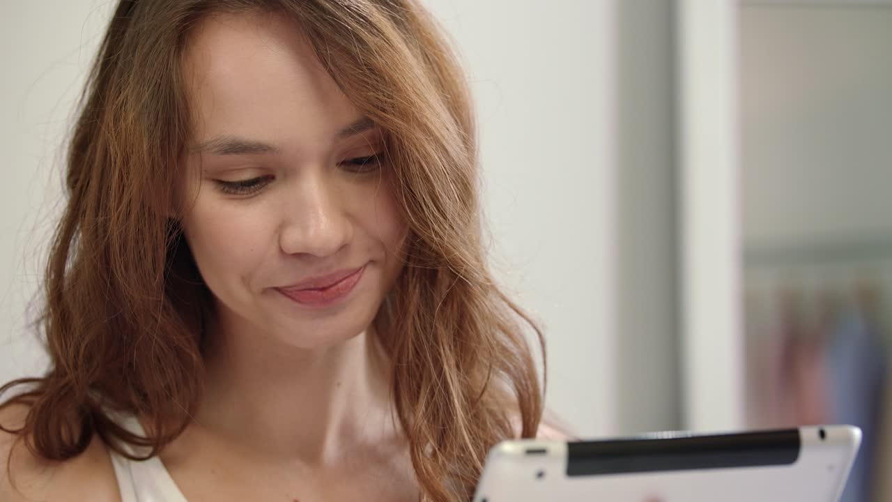 Glad kvinde kigger på tablet. Smilende kvinde med tablet.