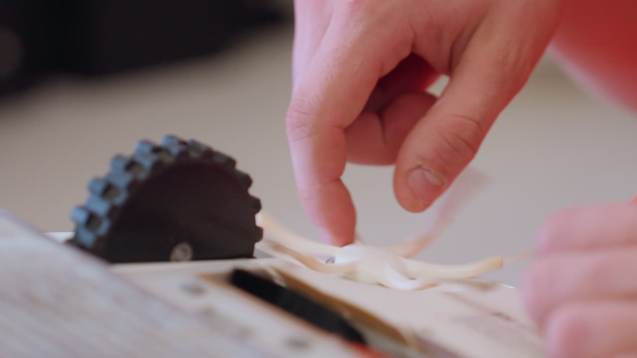 Extreme close up of hand adjusting side brush on robot vacuum during maintenance process showing careful repair and attention to household cleaning device for efficiency