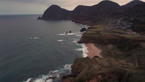 japan kyotango aerial drone panoramic fly above cliff and beach shoreline sunset pink skyline, establishing shot of mountains islands and natural environment japanese summer