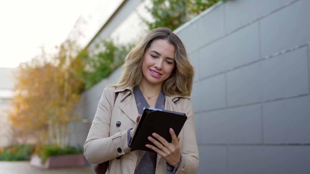 Smiling Young Woman Using a Digital Tablet Outdoors