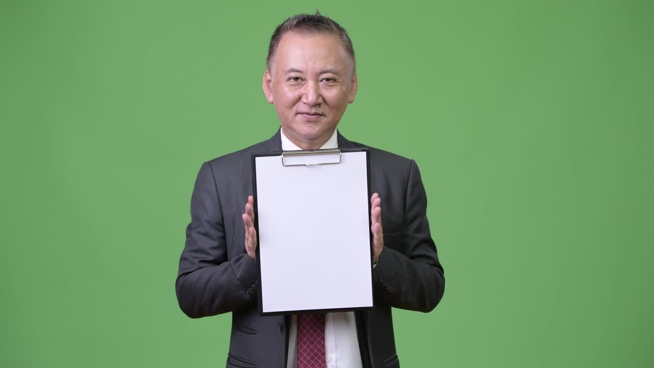 성숙 한 일본인 사업가 가 카메라 에 클립보드 를 보여 준다